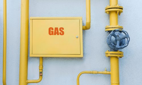 Gas meter box and pipes near grey wall outdoors